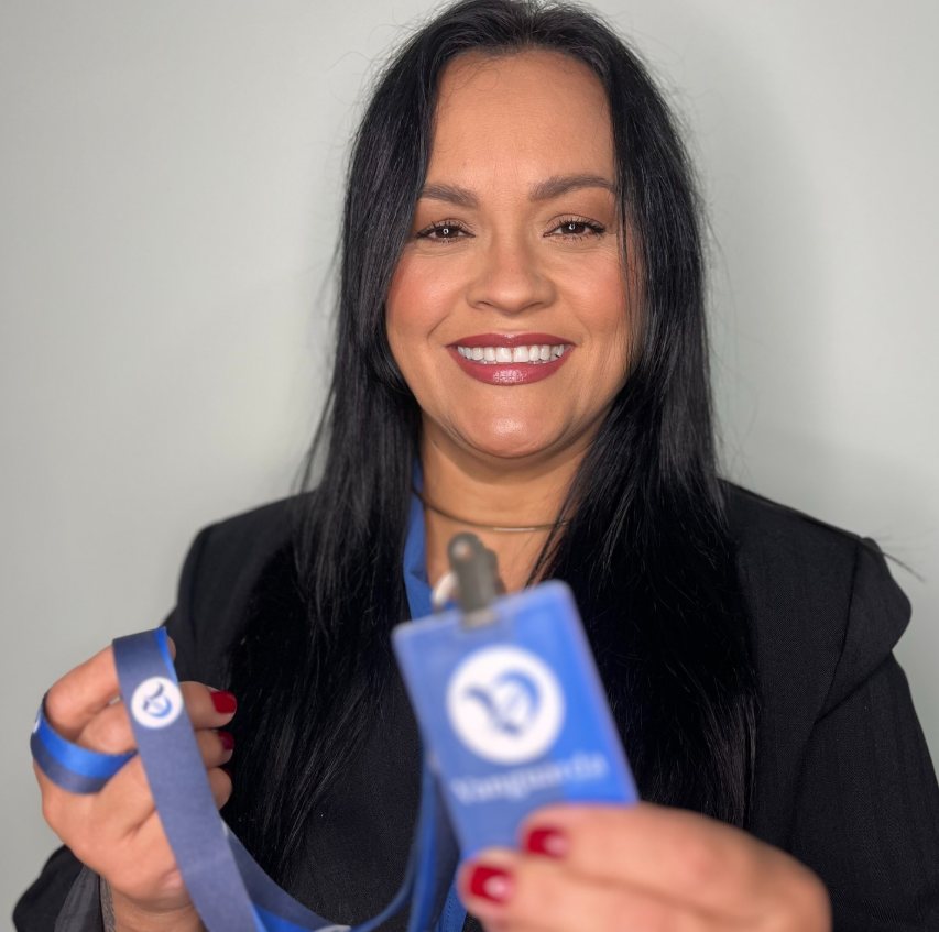 Angelita de Lima, fundadora da Vanguarda Promo, segurando um crachá com o logo da empresa